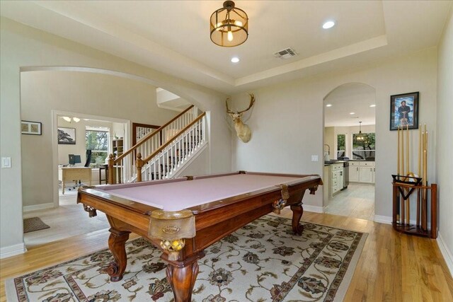 playroom with pool table, light wood-type flooring, and a tray ceiling