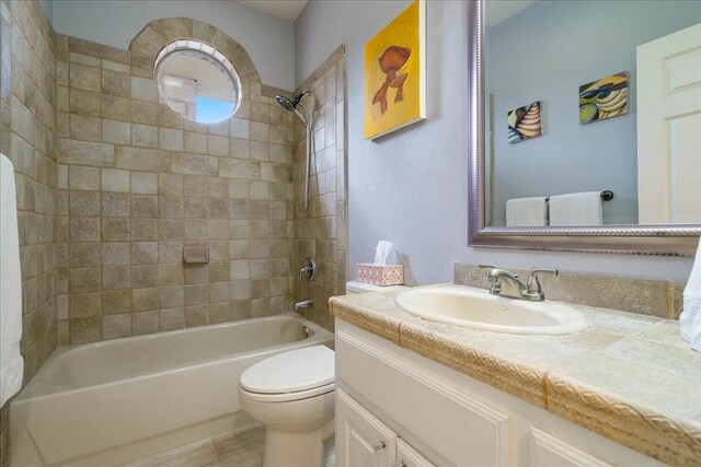 full bathroom with tiled shower / bath combo, vanity, and toilet