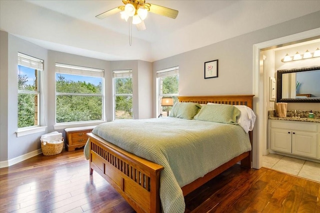 bedroom with ceiling fan, dark wood-type flooring, sink, and ensuite bath