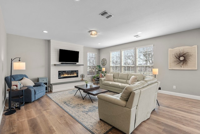 living room featuring a large fireplace and light wood-type flooring