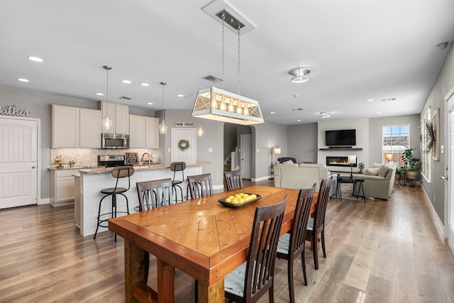 dining room with a large fireplace, sink, and light hardwood / wood-style floors