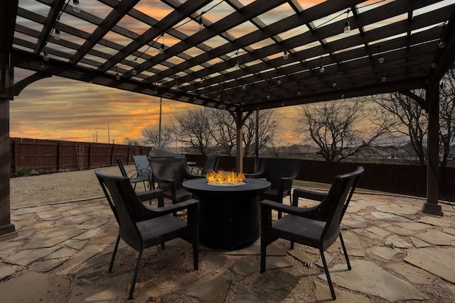 patio terrace at dusk featuring an outdoor fire pit and a pergola