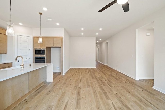 kitchen featuring light hardwood / wood-style floors, stainless steel oven, built in microwave, ceiling fan, and light brown cabinets