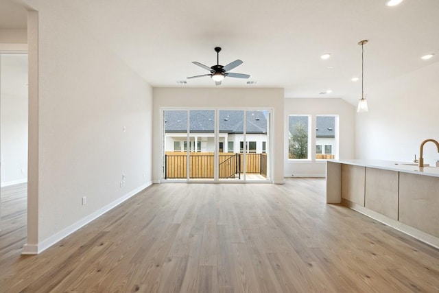 unfurnished living room with ceiling fan, light wood-type flooring, and sink