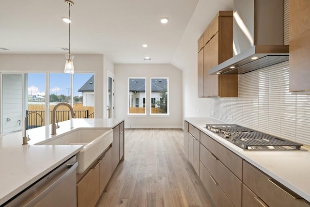 kitchen featuring stainless steel appliances, sink, tasteful backsplash, hanging light fixtures, and wall chimney range hood