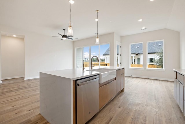 kitchen with an island with sink, light wood-type flooring, ceiling fan, sink, and stainless steel dishwasher