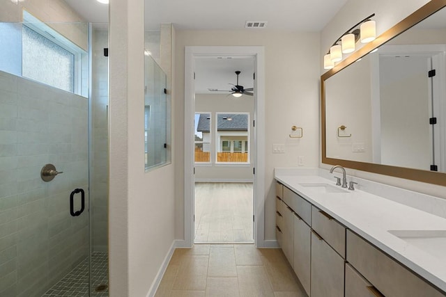 bathroom with ceiling fan, a shower with shower door, a wealth of natural light, and vanity