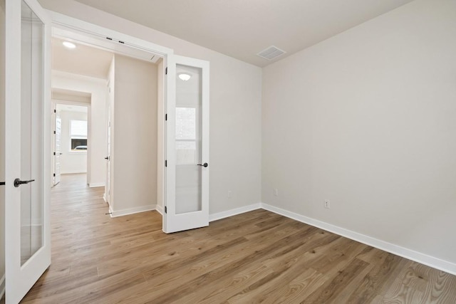 empty room featuring light wood-type flooring and french doors