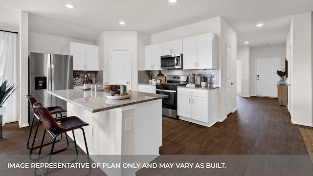 kitchen with white cabinets, stainless steel appliances, light stone counters, and a center island with sink