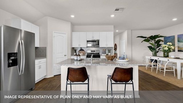 kitchen featuring light stone counters, white cabinets, appliances with stainless steel finishes, and an island with sink