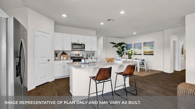 kitchen with white cabinets, stainless steel appliances, an island with sink, and dark hardwood / wood-style floors