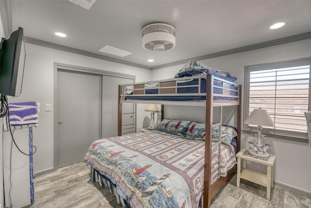 bedroom with a textured ceiling, a closet, crown molding, and wood-type flooring