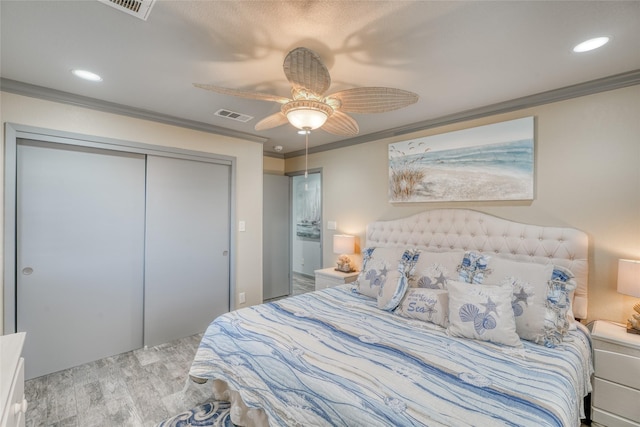 bedroom featuring ornamental molding, light wood-type flooring, ceiling fan, and a closet