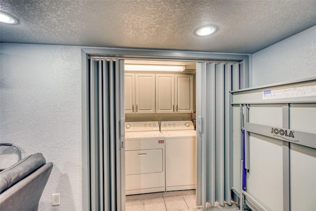 clothes washing area featuring a textured ceiling, separate washer and dryer, and cabinets