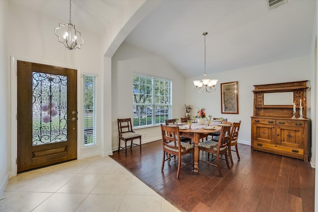 tiled dining room featuring a chandelier and vaulted ceiling