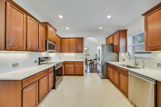 kitchen with stainless steel appliances, lofted ceiling, plenty of natural light, and sink