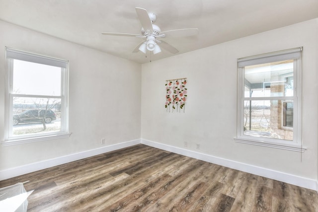 empty room featuring a healthy amount of sunlight, ceiling fan, and dark hardwood / wood-style flooring