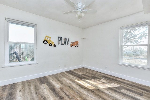 unfurnished room with ceiling fan, dark wood-type flooring, and plenty of natural light