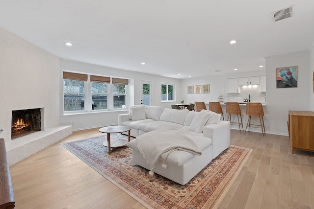 living room with a large fireplace and light hardwood / wood-style floors