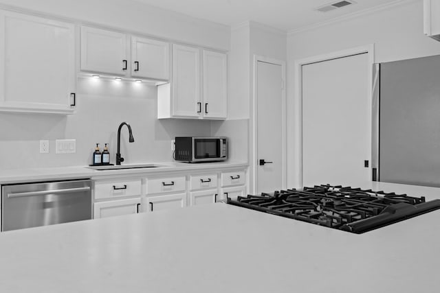 kitchen featuring sink, white cabinetry, ornamental molding, and appliances with stainless steel finishes