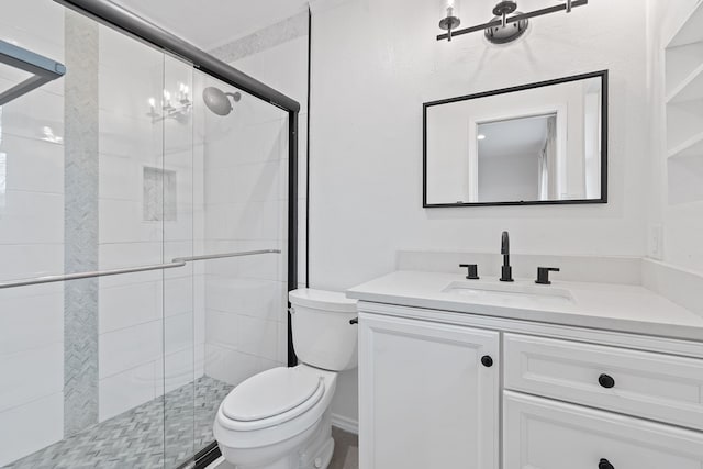 bathroom with toilet, a notable chandelier, walk in shower, and vanity