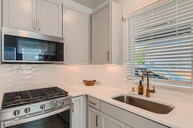 kitchen featuring sink, tasteful backsplash, light stone counters, and appliances with stainless steel finishes