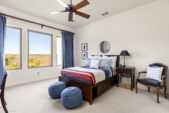 bedroom featuring ceiling fan, light carpet, and multiple windows