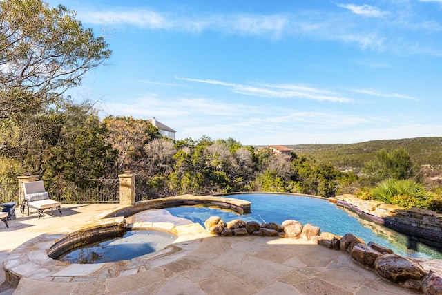 view of swimming pool featuring a patio and an in ground hot tub