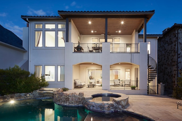 back of house featuring a pool with hot tub, a balcony, and a patio