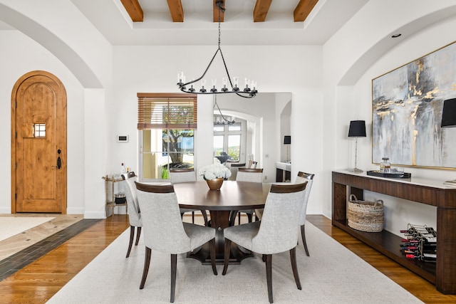 dining space featuring a notable chandelier, dark hardwood / wood-style flooring, and beamed ceiling