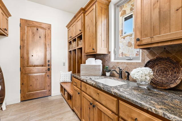 kitchen with dark stone countertops, tasteful backsplash, and sink