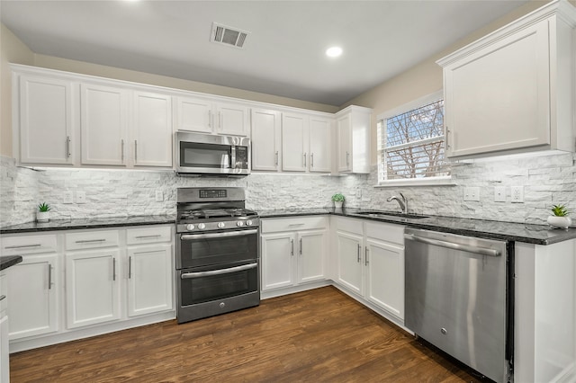 kitchen featuring stainless steel appliances, sink, white cabinets, dark stone countertops, and dark hardwood / wood-style floors