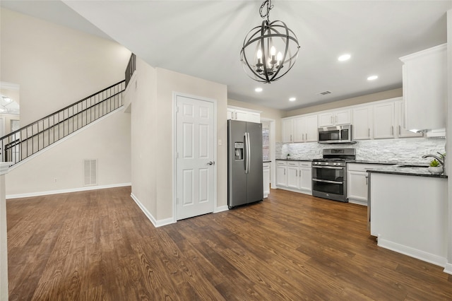 kitchen with a chandelier, appliances with stainless steel finishes, sink, white cabinetry, and backsplash