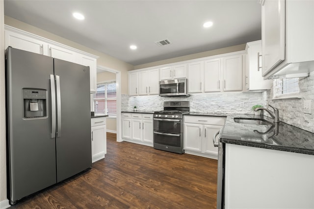 kitchen featuring stainless steel appliances, sink, white cabinetry, dark stone countertops, and dark hardwood / wood-style flooring