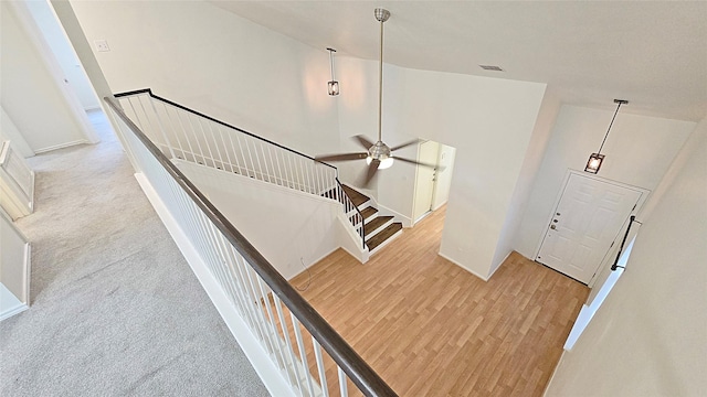 staircase featuring ceiling fan and carpet flooring