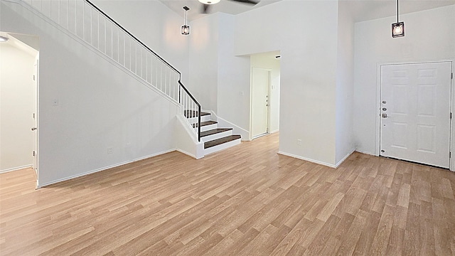 foyer with a high ceiling, light wood-type flooring, and ceiling fan