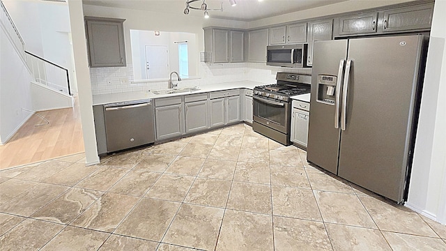 kitchen featuring stainless steel appliances, sink, light tile patterned floors, decorative backsplash, and gray cabinets