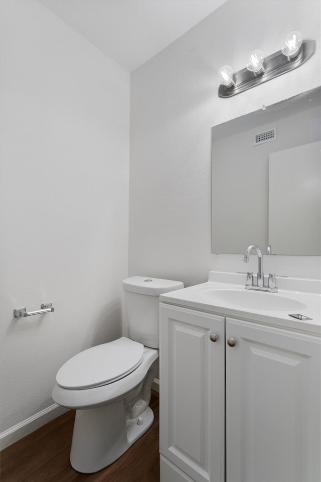 bathroom featuring toilet, vanity, and hardwood / wood-style floors