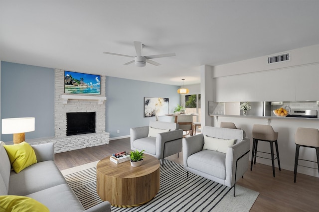 living room featuring dark hardwood / wood-style flooring, a fireplace, and ceiling fan