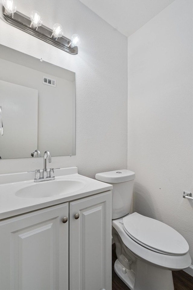 bathroom featuring toilet, vanity, and hardwood / wood-style flooring