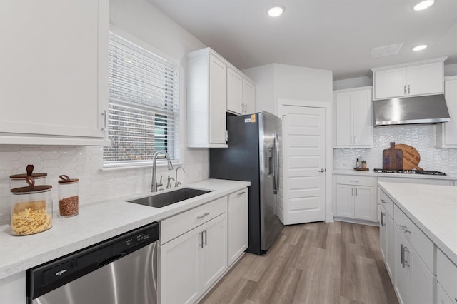 kitchen with stainless steel appliances, sink, white cabinets, light wood-type flooring, and tasteful backsplash