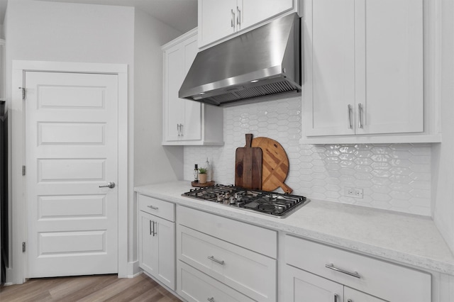 kitchen with white cabinetry, light stone counters, tasteful backsplash, light hardwood / wood-style flooring, and stainless steel gas stovetop