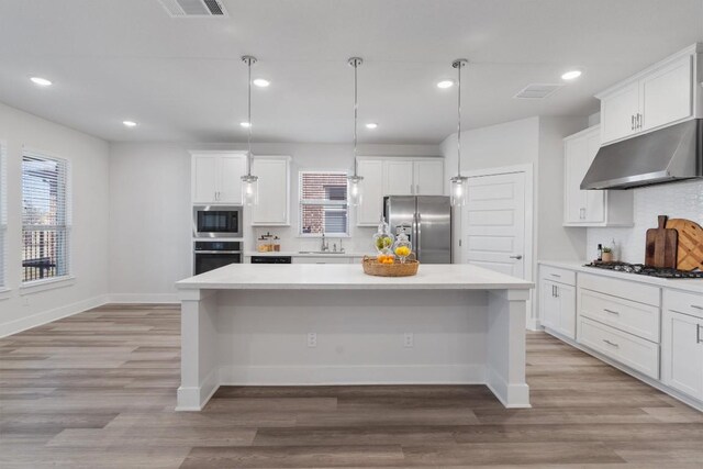 kitchen featuring stainless steel appliances, sink, decorative backsplash, hanging light fixtures, and a kitchen island