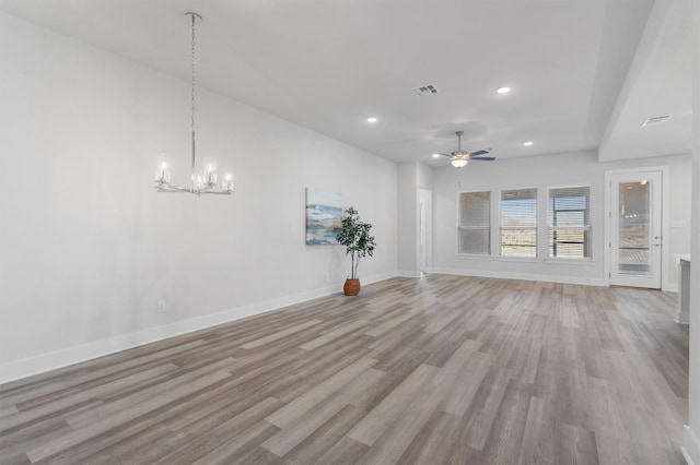 unfurnished living room with ceiling fan with notable chandelier and light hardwood / wood-style flooring