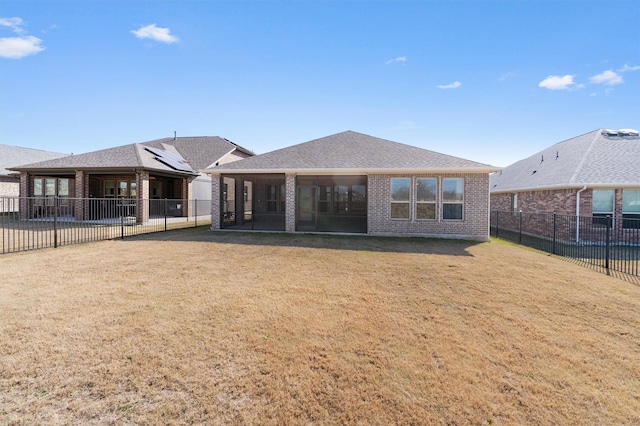 back of property with a sunroom and a lawn