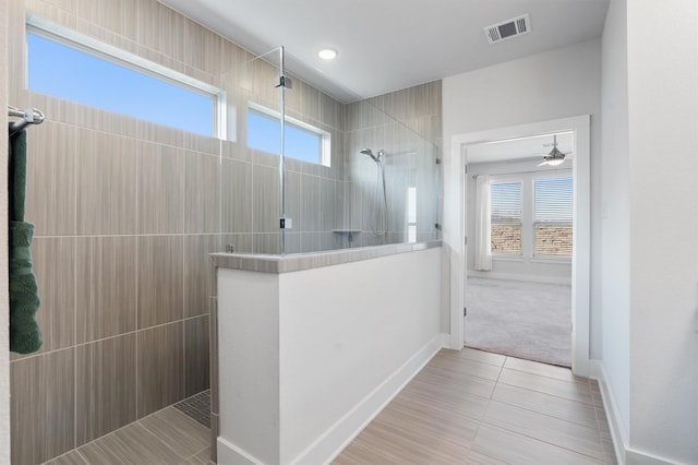 bathroom featuring tile patterned flooring, a tile shower, and ceiling fan