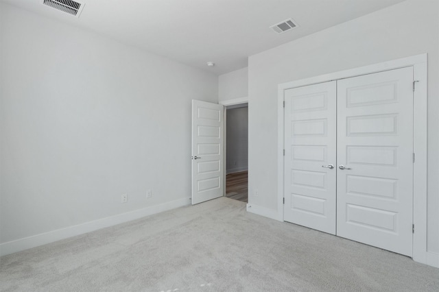 unfurnished bedroom with a closet and light carpet