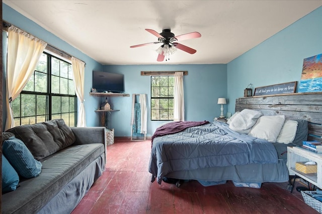 bedroom with ceiling fan, wood-type flooring, and multiple windows