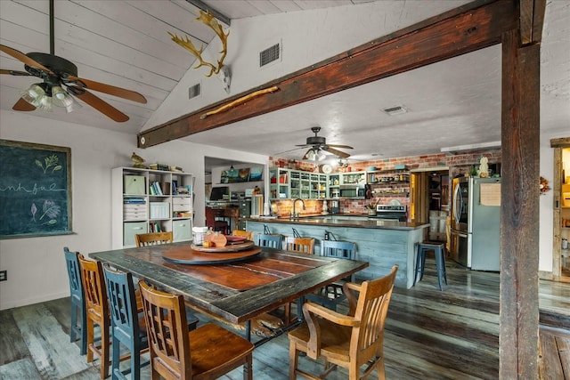 dining room featuring lofted ceiling, hardwood / wood-style flooring, and wet bar