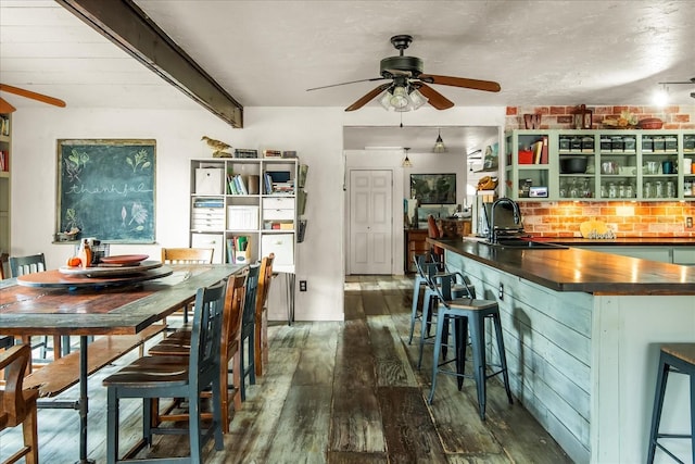 dining area featuring beam ceiling, ceiling fan, dark hardwood / wood-style flooring, and sink